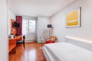 a hotel room with a bed and a desk with a computer at Sorell Hotel Sonnental in Dübendorf
