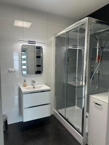 a white bathroom with a shower and a sink at Apartament NATURA z widokiem na jezioro in Iława