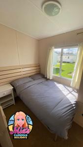 a bedroom with two beds and a window at The Cosalt Torbay Caravan in Ingoldmells