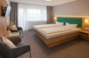 a hotel room with a large bed and a chair at Hotel Seestern in Wasserburg am Bodensee