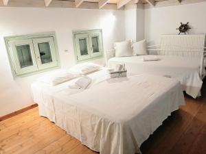 two beds with white sheets in a room at Liopi Village Andros in Órmos