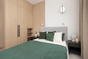 sypialnia z zielonym i białym łóżkiem i szafkami w obiekcie JTB Brama Portowa w Szczecinie