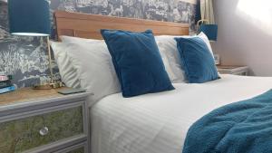 a bedroom with a bed with blue and white pillows at Invergarry Room Only Guest House For Adults in Windermere