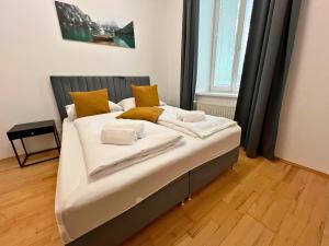 1 cama blanca grande con almohadas amarillas en una habitación en Leoben City Apartments - Premium Apartments 24 7, en Leoben