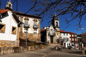 un antiguo edificio con una torre de reloj en una calle en Vouga Lodge, en São Pedro do Sul