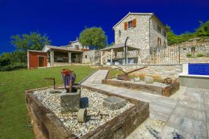 ein Steinhaus mit einem Hof mit einer Feuerstelle in der Unterkunft Beautiful stone Villa with private pool near Rabac in Barbići