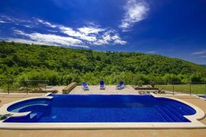 einen Pool mit zwei blauen Stühlen und einem Berg in der Unterkunft Beautiful stone Villa with private pool near Rabac in Barbići