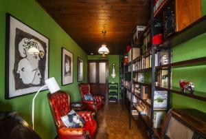 biblioteca con paredes verdes, sillas rojas y estanterías en Casa Robina en Barga