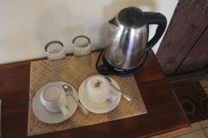 een koffiepot op een tafel met twee kopjes en schotels bij Temple Cafe & Cottages in Candidasa