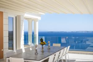 a dining room table with chairs and a view of the ocean at Villa Monte Leone by Konnect with Pool, Hot Tub, Spa Room & Stunning Seaview in Pyrgi
