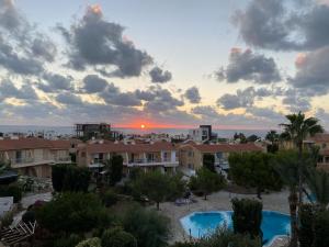 a view of a resort with a sunset in the background at Newly renovated- Regina Gardens 1, Venus Beach 500 m, Sea&Sunsets view, license oo12075 in Paphos