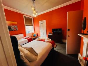 a bedroom with orange walls and a bed and a couch at horn and trumpet in Bewdley