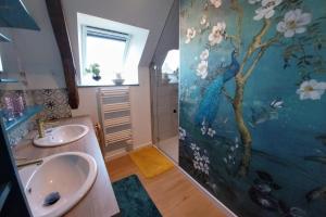 La salle de bains est pourvue de 2 lavabos et d'une peinture murale en paon. dans l'établissement La Osmonière - Maison 6 personnes - Tout inclus, à Saint-Méloir-des-Ondes