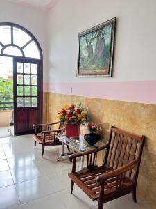 una habitación con bancos y una mesa con flores. en Khách sạn Khoa Đạt en Di Linh