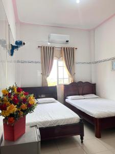 1 dormitorio con 2 camas y un jarrón de flores en Khách sạn Khoa Đạt en Di Linh
