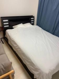 1 cama con sábanas blancas y cortina azul en tokyo Large family vacation rentals en Tokio