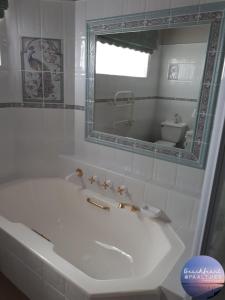 a white bathroom with a tub and a mirror at By The Beach - Beachfront Apartment & Home in Langebaan