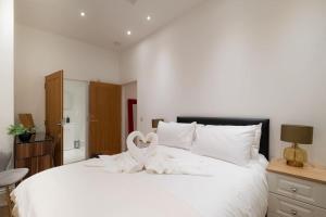 Un dormitorio con una cama blanca con una cinta blanca. en 2 Bed 2 Bath Spacious Apartment in Central Aberdeen en Aberdeen