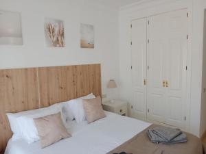 a bedroom with a white bed with white pillows at El Oasis de Roda Golf Apartment in San Javier +14 photos
