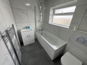 a bathroom with a tub and a toilet and a sink at Entire three bedrooms house in London