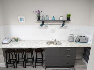 a kitchen counter with three bar stools and a sink at Serenity Ballycastle in Ballycastle +11 photos
