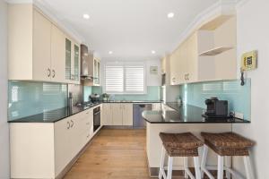 a kitchen with white cabinets and a black counter top at Perfect Beach getaway in Narrabeen