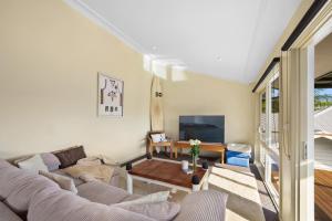 a living room with a couch and a tv at Perfect Beach getaway in Narrabeen