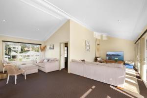 a living room with white furniture and a large window at Perfect Beach getaway in Narrabeen