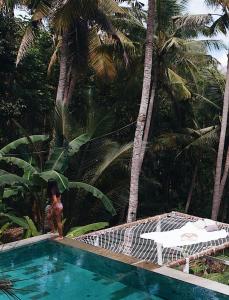kobieta stojąca obok basenu z palmami w obiekcie SPICE TRADER w mieście Nusa Penida