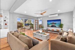 a living room with two couches and a ceiling fan at Beachside Magic - Footsteps to the Beach in Narrabeen