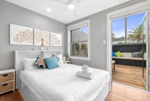 a bedroom with a large white bed and a balcony at Beachside Magic - Footsteps to the Beach in Narrabeen