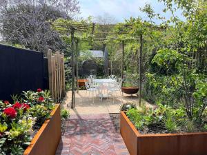 un jardín con un patio con una mesa y flores en South Downs Cottage With Views, en Poynings