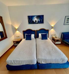 ein Schlafzimmer mit einem blauen und weißen Bett mit zwei Kissen in der Unterkunft Domina coral Bay diving Spa casino sultan beach in Sharm El Sheikh