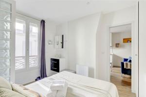 a white bedroom with a bed and a window at Invalides & Eiffel Tower - CityApartmentStay in Paris