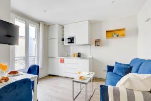 a living room with a blue couch and a kitchen at Invalides & Eiffel Tower - CityApartmentStay in Paris