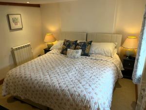 1 dormitorio con 1 cama con edredón blanco y 2 lámparas en South Downs Cottage With Views, en Poynings
