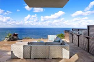 een patio met een bank en de oceaan op de achtergrond bij Curley Sunrise - Oceanfront in Curl Curl