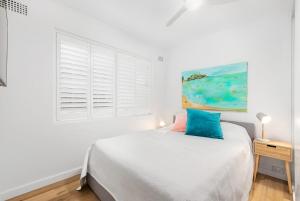 a white bedroom with a bed and a window at Beachfront Magic Unbeatable Location in Sydney