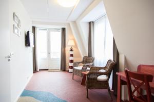 a hallway with chairs and a table and a window at Strandhotel Noordzee in De Koog