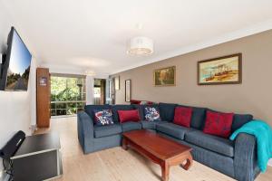 sala de estar con sofá azul y almohadas rojas en Hidden Hideaway - Family Friendly, en Sídney