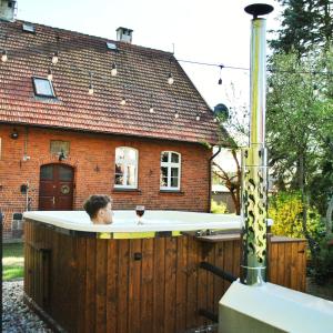 a boy in a hot tub in front of a house at Pokrzepka in Spychowo