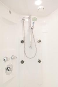 een douche met een douchekop in de badkamer bij Strandhotel Noordzee in De Koog