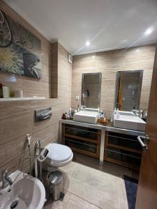 uma casa de banho com 2 lavatórios, um WC e um espelho. em Private room with view em Estoril