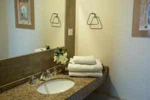 a bathroom with a sink and a mirror and towels at Cabaña Atardecer - Finca La Falda - Salta in Cerrillos