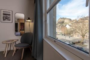 a room with a window with a chair and a table at Apex City of Edinburgh Hotel in Edinburgh