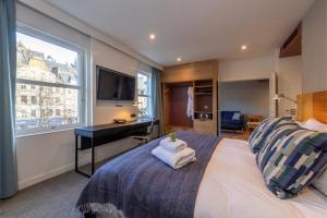 1 dormitorio con 1 cama, escritorio y ventana en Apex City of Edinburgh Hotel, en Edimburgo