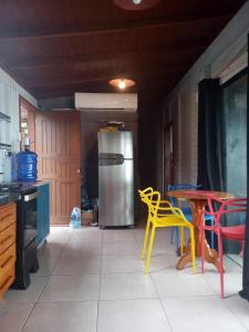 a kitchen with yellow chairs and a table and a refrigerator at Hygge Sunset House in Ilha do Mel