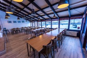 a row of tables and chairs in a room with windows at The Northern Comfort Inn in Ólafsfjörður