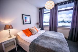 a bedroom with a bed with orange pillows and a window at The Northern Comfort Inn in Ólafsfjörður