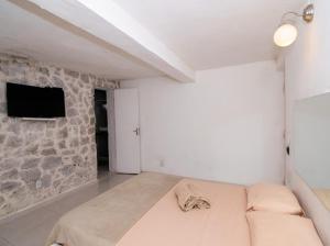 Habitación blanca con sofá y pared de piedra. en Pousada Kico en Búzios